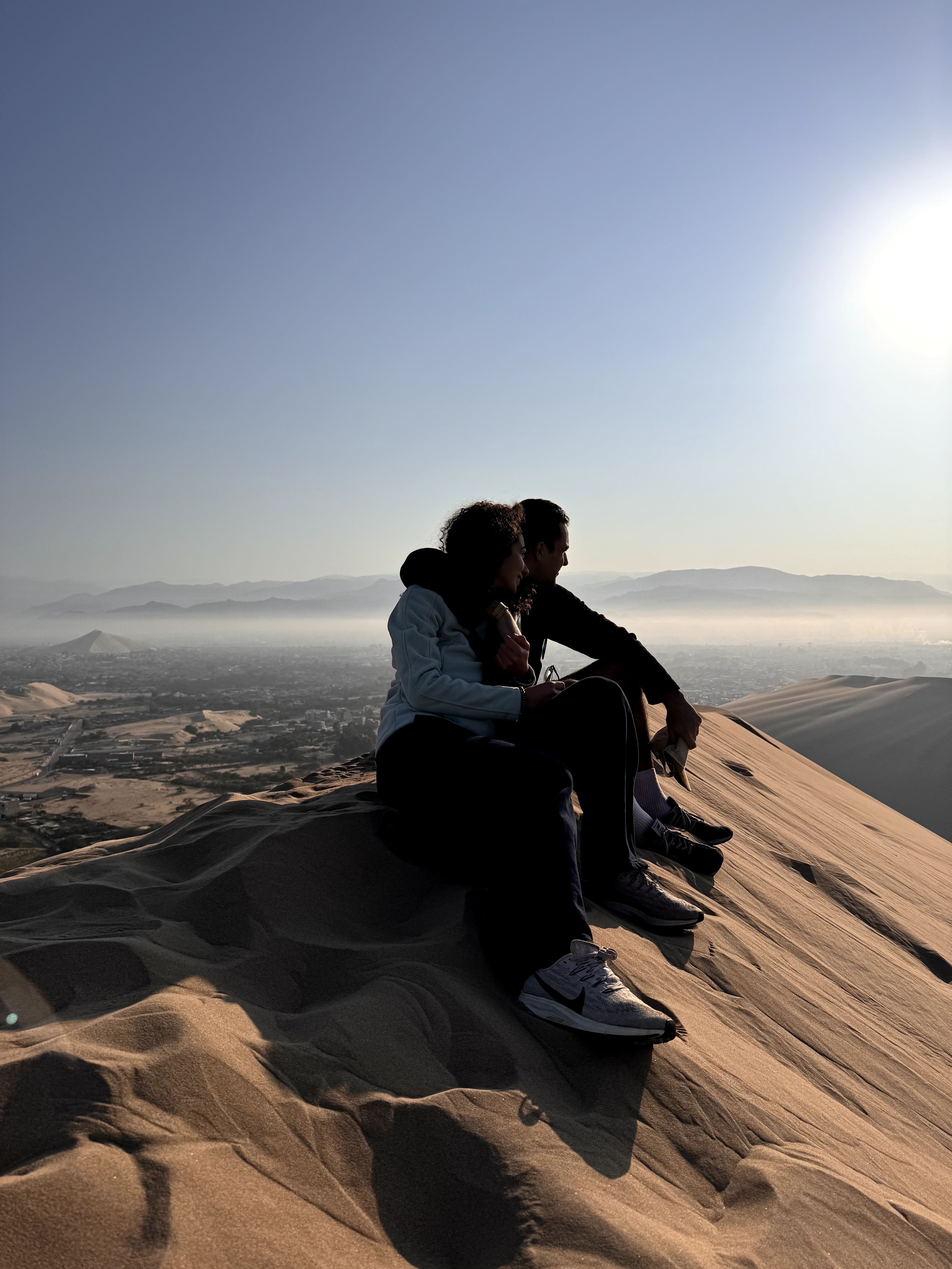 Adam et Soraya assis sur une dune au lever du soleil, Huacachina